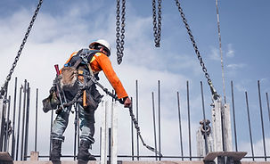Un trabajador vistiendo equipos de seguridad y un arnés trabajando en un tejado.