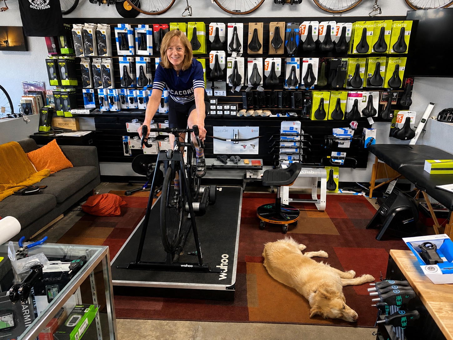 A rider on the fitting trainer with a shop dog resting nearby