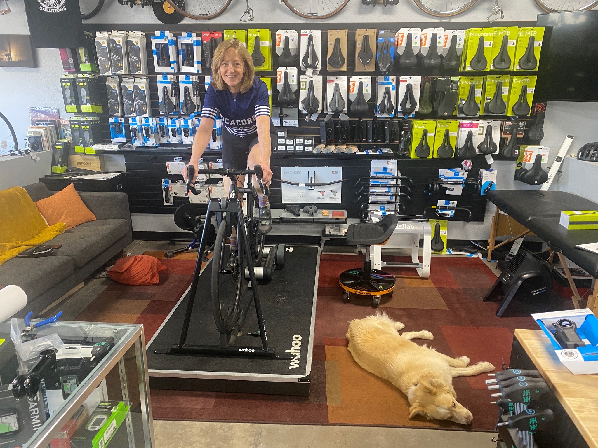 A rider on a road bike in the fitting studio with a shop dog nearby