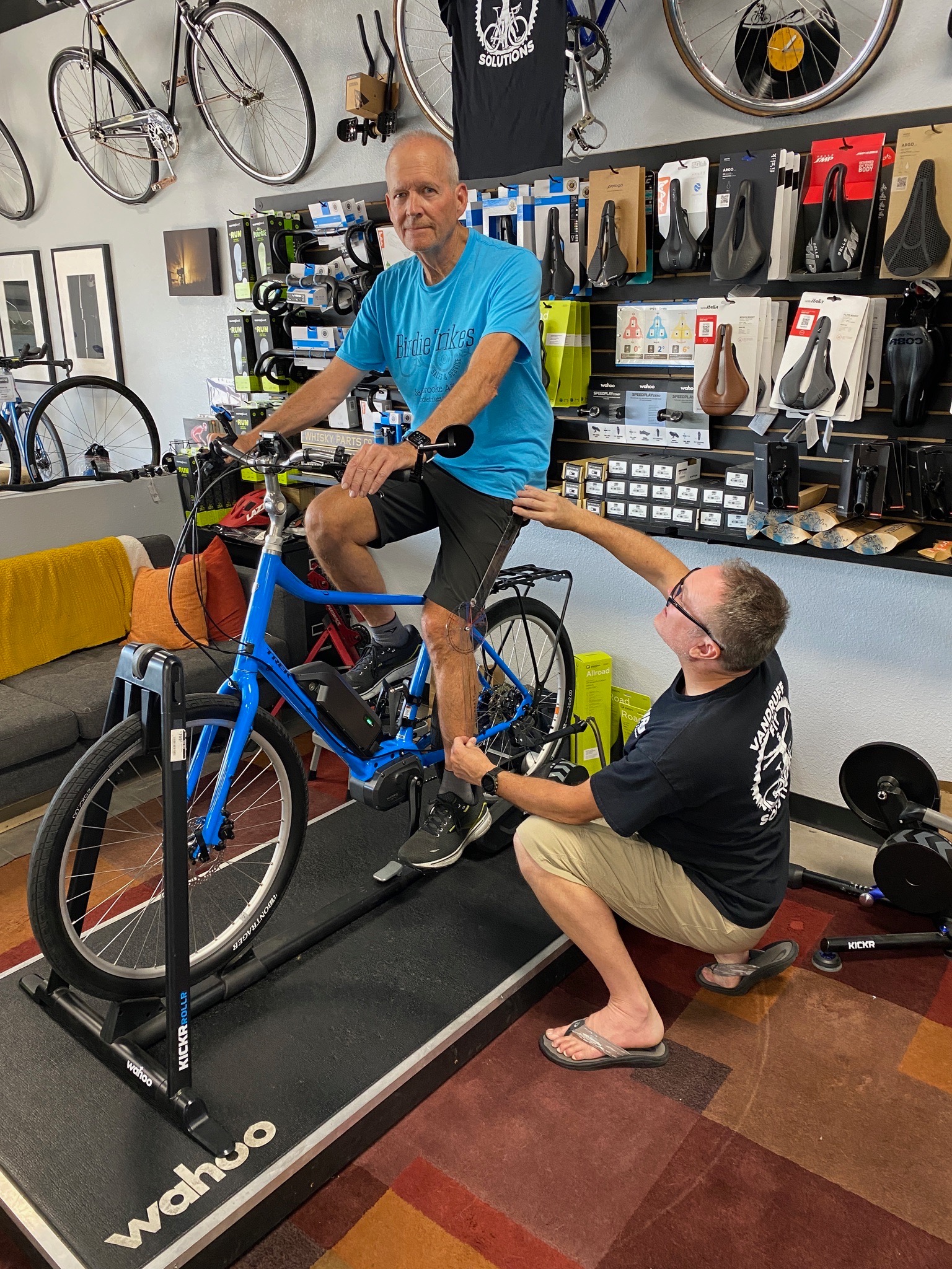 Tyler adjusting the fit for a rider in a blue shirt on a comfort bike