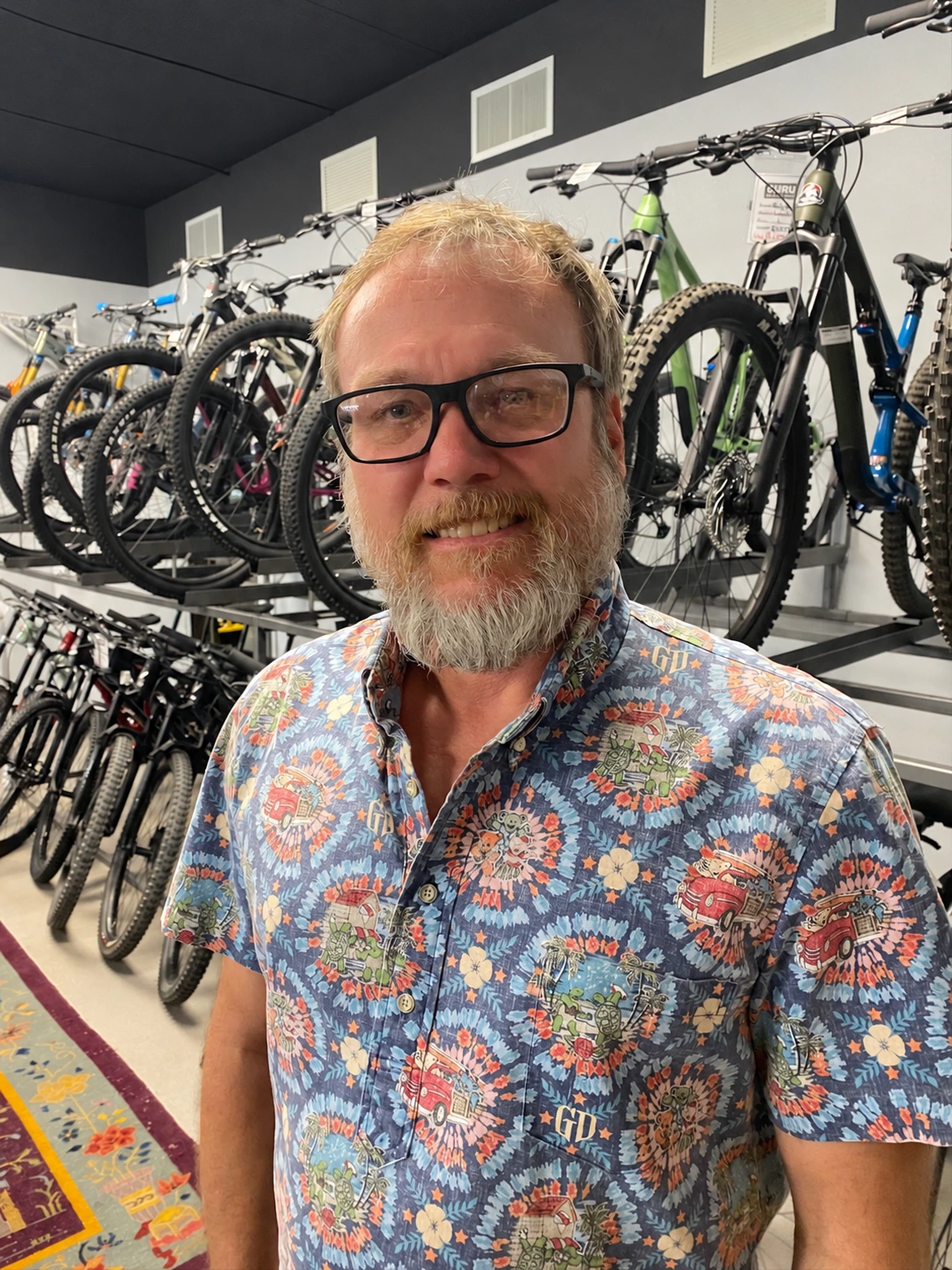 Tyler Vandruff inside Guru Bikes with mountain bikes behind him
