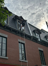Technicien en accès sur corde réalisant des travaux de calfeutrage extérieur sur un immeuble à Montréal