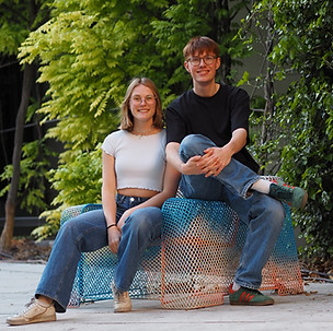 Die beiden Gründer sitzen im Freien entspannt auf einer Skulptur.