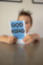 A young boy looking closely at a Rooted dinner table devotional card during family conversation time.