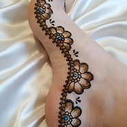 Natural henna tattoo with glitter and rhinestones, beautiful floral design on foot_