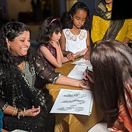 Adults and kids having fun and gathering around a table where they are getting henna tatto
