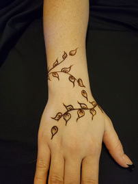 high speed, henna artist gives a party guest a professional, dainty, bracelet style wrist design, of an elegant vine at a corporate event in Scottsdale Arizona.