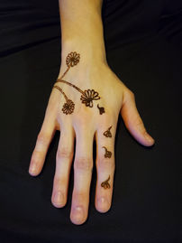 simple, delicate, cute, whimsical dandelion henna tattoo on the back of the hand. this popular dandelion design shows 3 simple dandelions and one trails up the pointer finger.