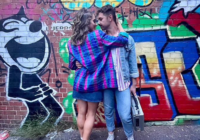 A couple hugging in a laneway with graffiti 