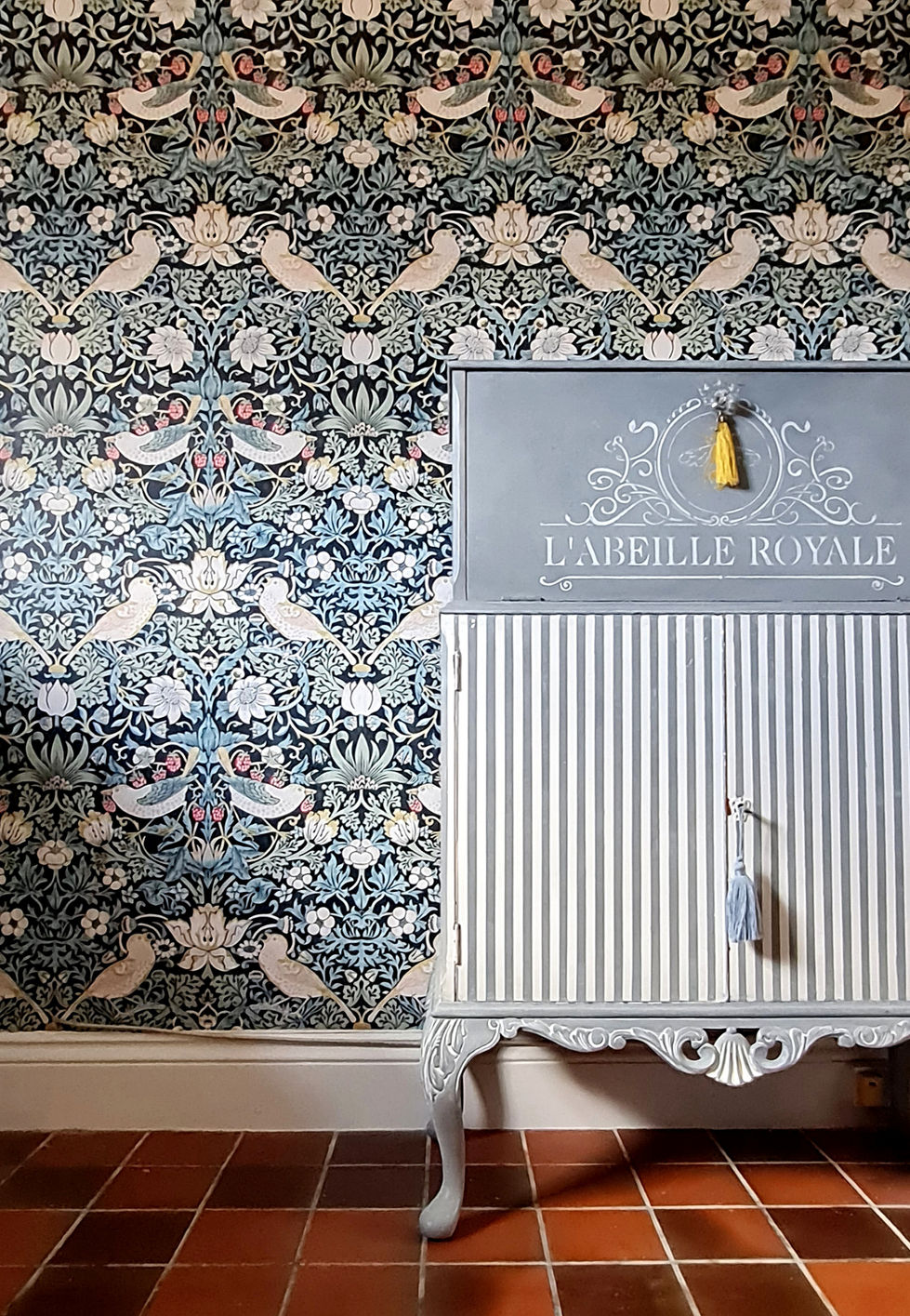 painted striped cupboard against William Morris Strawberry Thief wallpapered wall