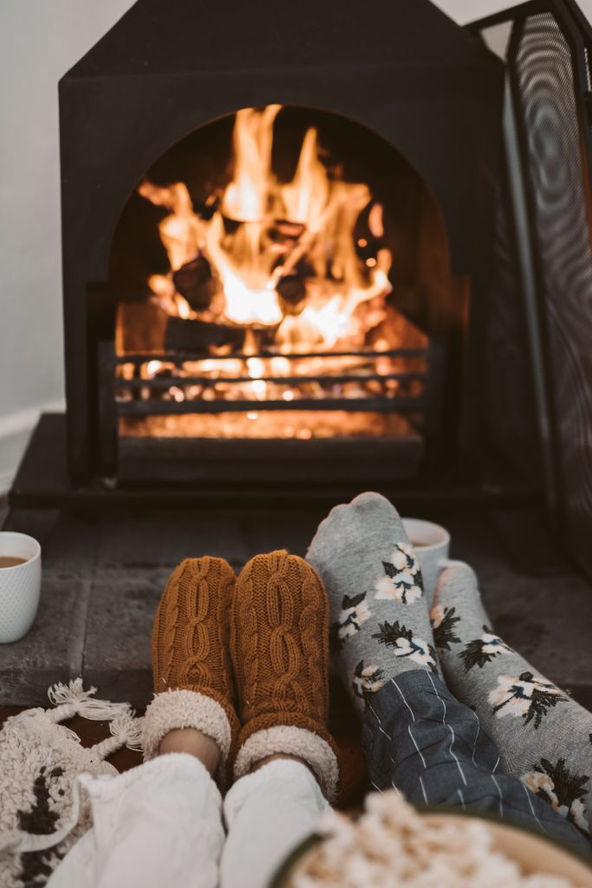 A woman with mug sitting near fire.
