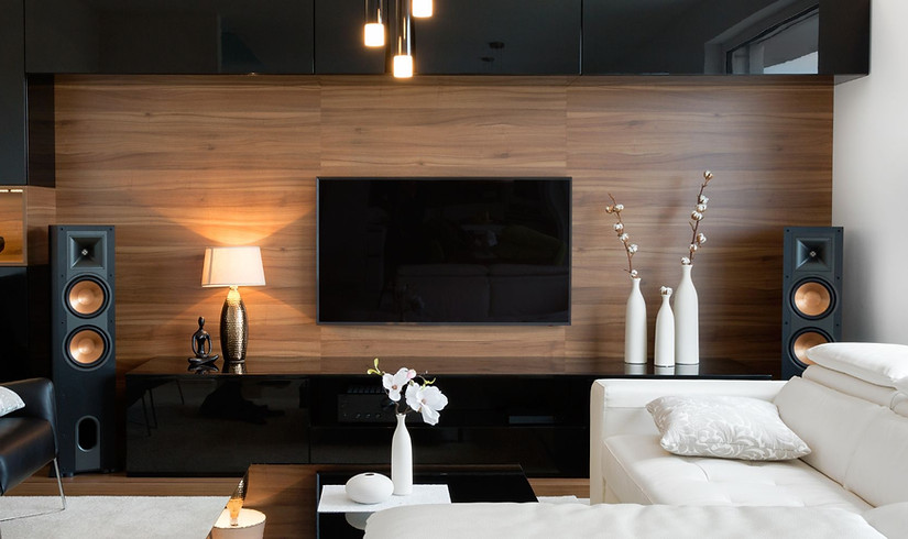 Wohnwand in Nuss mit schwarzen Fronten in Klavierlack, hochglänzend. Mit einem Flat - TV und Lautsprechern