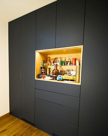 ein schwarzer Schrank mit beleuchteter Aussparung, das als Regal dient. Dort befinden sich viel Sammlerstücke ausgestellt