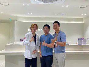 A photo of the patient, the doctor, and a coordinator in front of Banobagi Dermatology Clinic