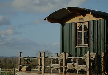 Smart, luxury, forest green shepherd's hut with outdoor decking in the countryside