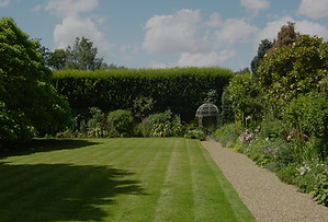 Walled Garden with elegant flowerbeds, mowed grass, leafy trees and blue skies