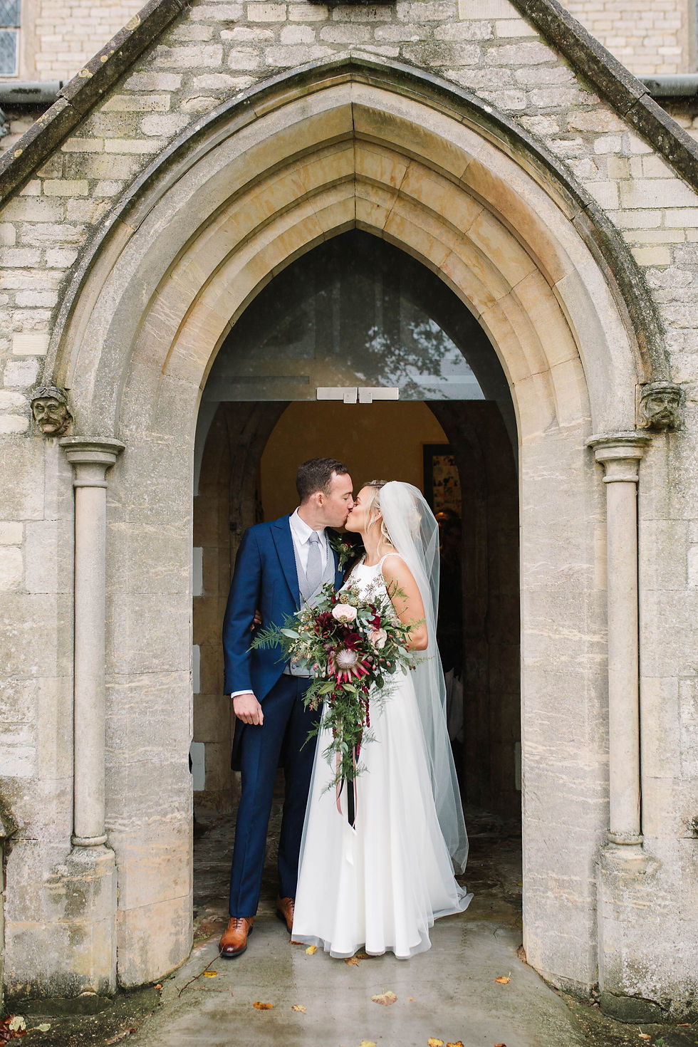 bride and groom kissing outside church entrance