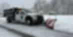 white salt truck plowing snow off a roadway 