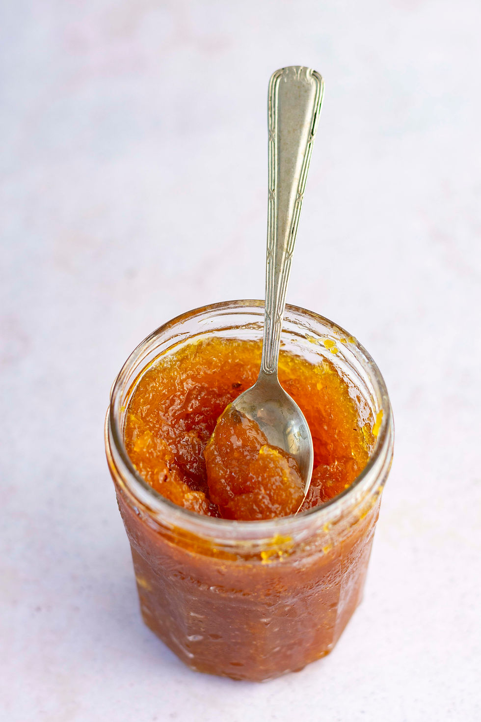 frasco de vidrio con mermelada de manzana caramelizada y cuchara