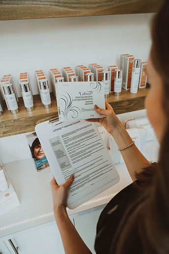 A woman holding a package and instructions for latisse eyelash enhancement at Organic Glow Medical Aesthetics in Kelowna.