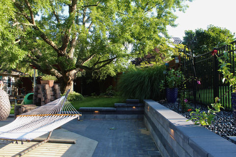 Backyard pool patio with hammock and retaining wall by Yard Shark Lawn Care
