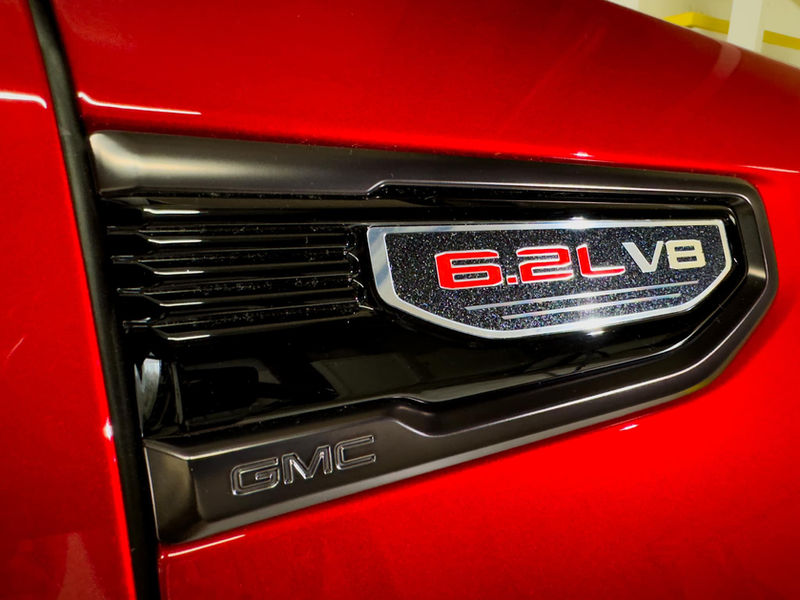 Red car side fender with "6.2L V8" and "GMC" badge.