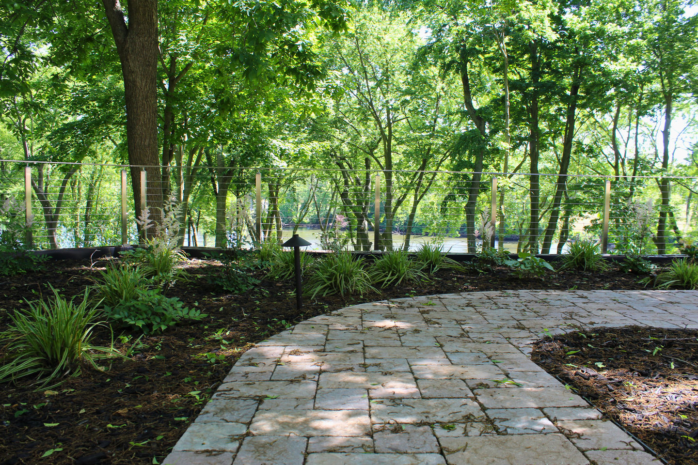 Curved paver walkway with landscaping and natural wooded setting