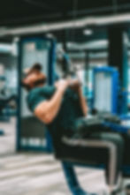 A man performing pull-downs at the gym, focusing on his workout as he uses a cable machine to strengthen his back and arms.