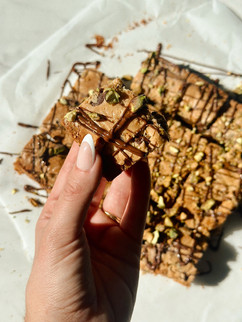 Gluten-free dark chocolate pistachio sea salt blondies sliced into squares on parchment paper.