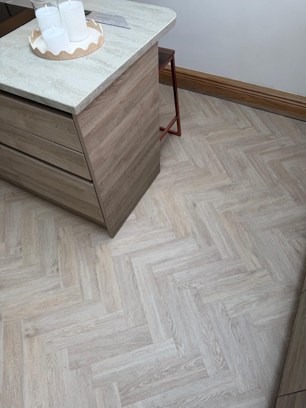 Pale wood-effect herringbone flooring around a kitchen island