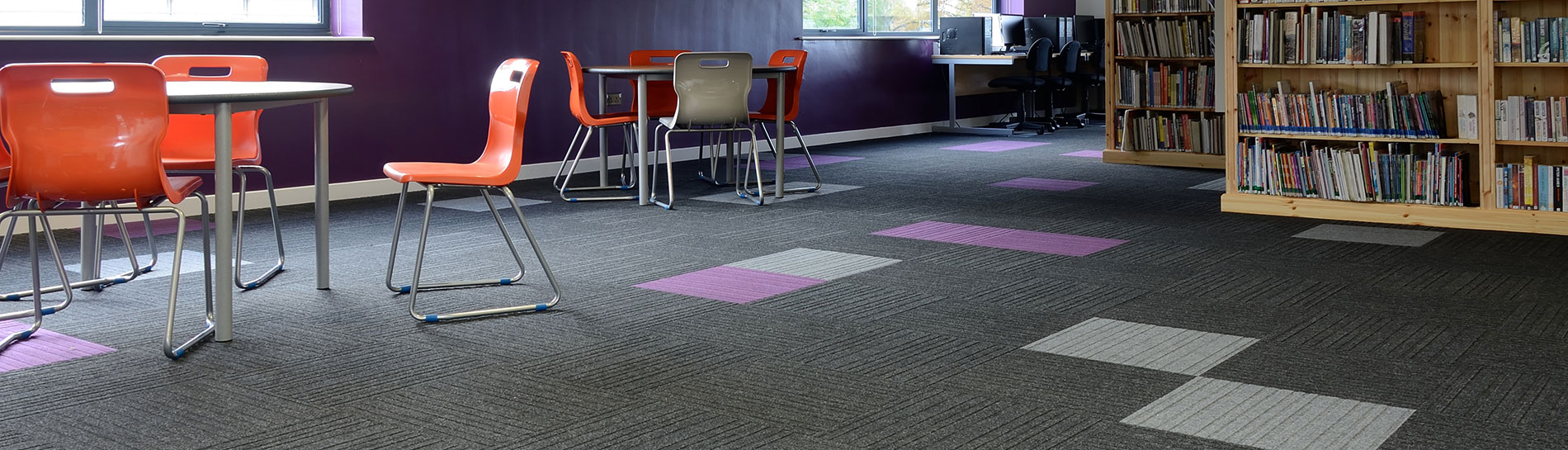 Burmatex manufacturer photograph of grey and purple carpet tiles in a college library