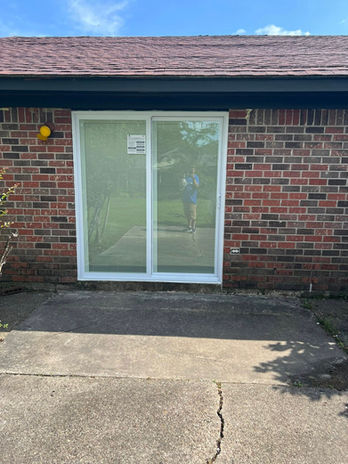 Sliding glass door on brick wall. New construction home exterior, sunny day.