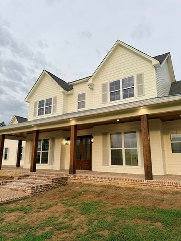 Two-story cream house with a wide dark-columned front porch