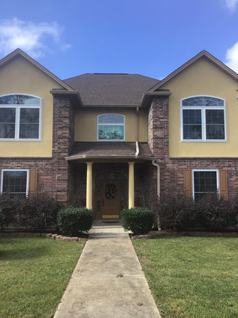 Residential building with windows and a path to the front door, under a blue sky.