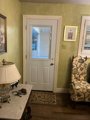 White door with glass panel, leading to another room, in a house.