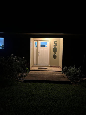 Front door illuminated at night with address 506. Door Installation, Blazier Unlimited.