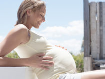 Pregnant woman gently holding belly in natural light