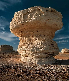 une formation rocheuse naturelle en forme de champignon ou de piédestal dans un paysage désertique.