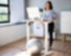 Office worker stretching beside the desk to relieve back and neck tension.