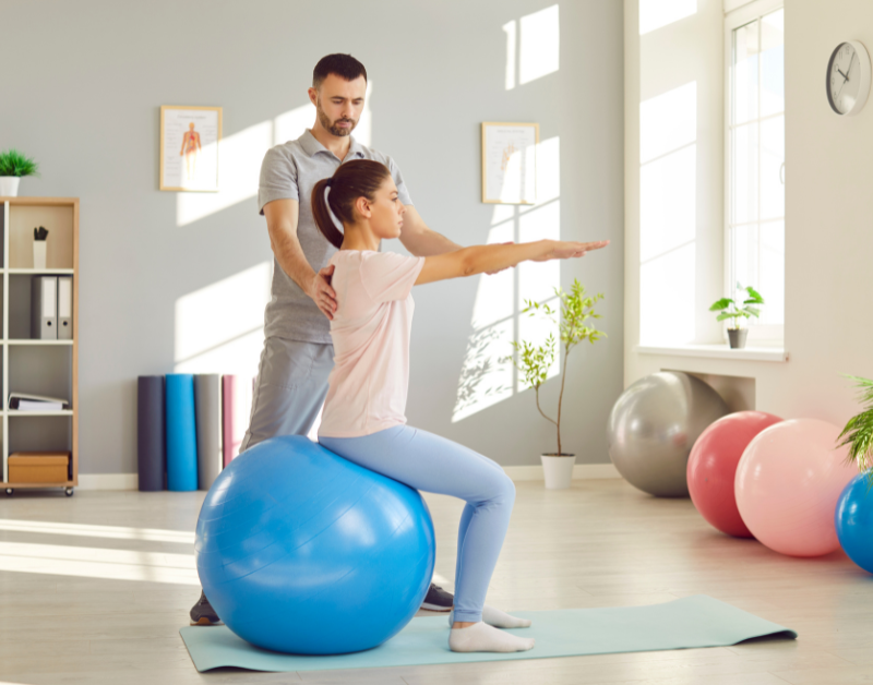 Physical therapist helping patient with spine-strengthening exercises.
