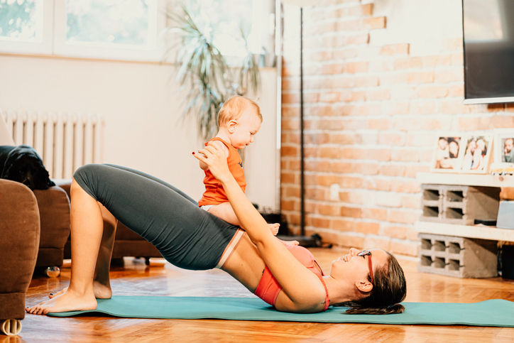 Woman doing Pilates with baby nearby