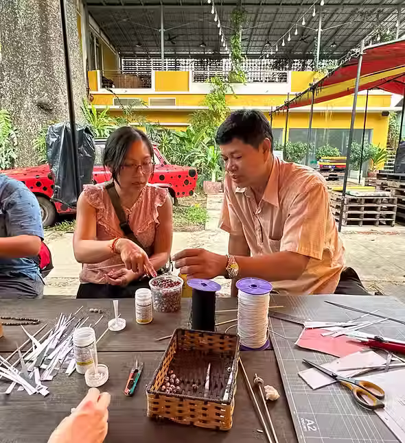 Tourists creating their own paper beads jewelry during handicraft class