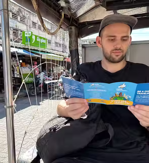 Tourist reading 7 Tips for Travelers booklet during ChildSafe Experiences tuk tuk tour