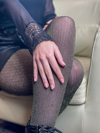gezeigt wird eine schwarze Strumpfhose mit Goldglitzereffekten von Falke zu einem Shirt von Nina von C, davon ist aber nur der schicke Armabschluß zu sehen, der ebenfalls mit goldglitzer versehen ist. Das Model hat farblich passende Nägel, ihre Hand liegt auf der Strumpfhose
