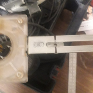 Power tool being modified on a bench with toolbox in background.