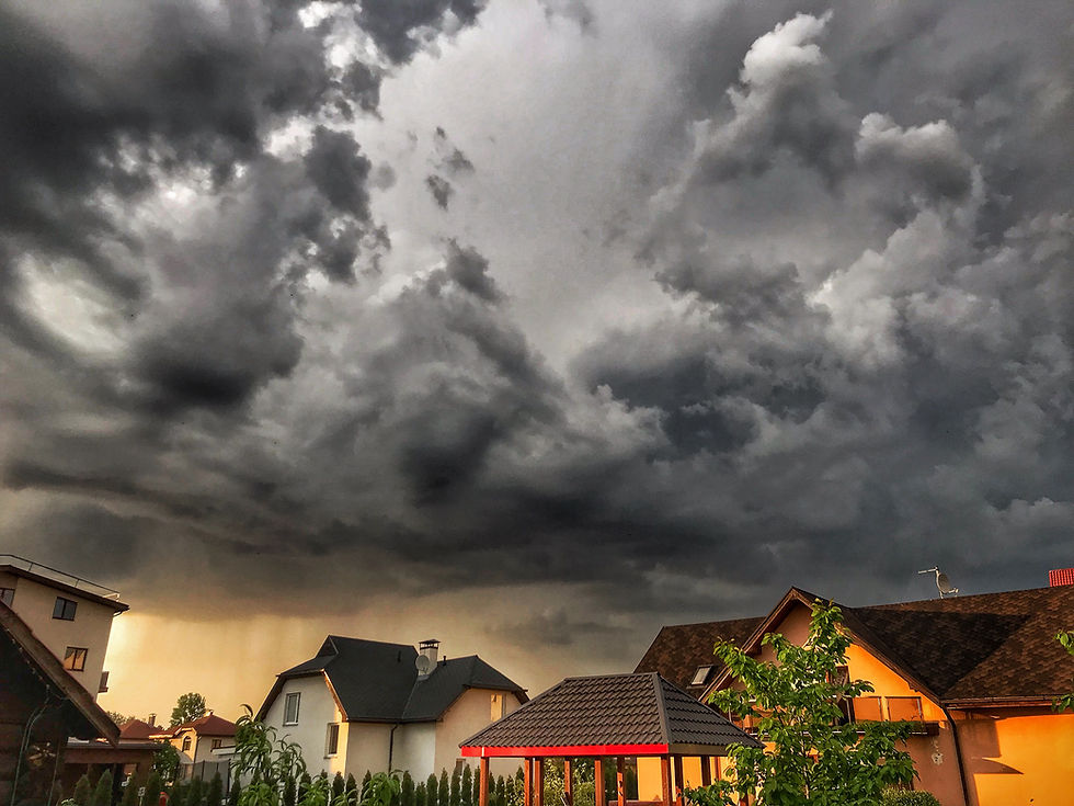 Dark storm clouds forming over a residential neighborhood with homes beneath an approaching severe weather system.