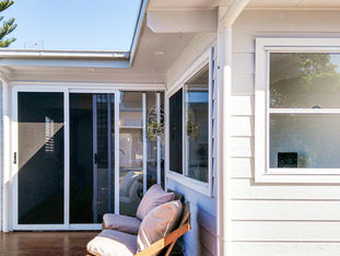 Large sliding doors and windows open out to wrap around timber deck with comfy lounge chairs