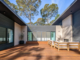 A generous hardwood deck extends the living space toward the riparian reserve, engaging with the broader site.