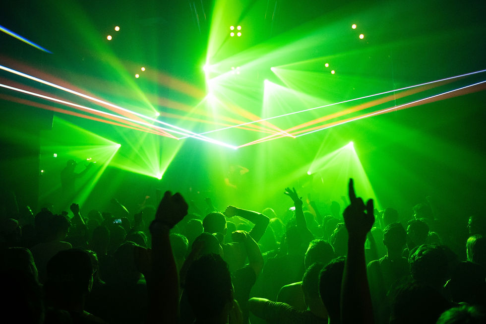 A dim, atmospheric nightclub with stage lights and a hazy crowd
