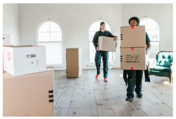 Movers carrying boxes inside a bright home